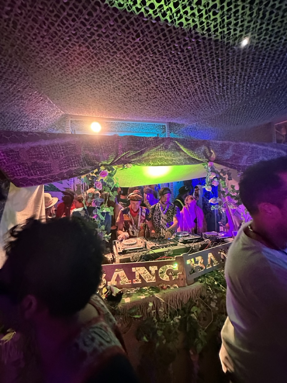 DJ set in progress inside a decorated Camp Bang Bang booth at night.